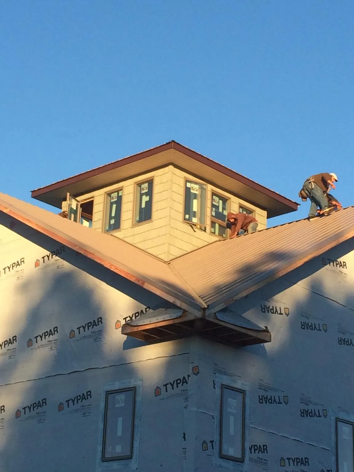 Roofers working around a rooftop cupola on a new metal roof at sunset — Roof Waterproofing in Lockport by Roofing Brothers